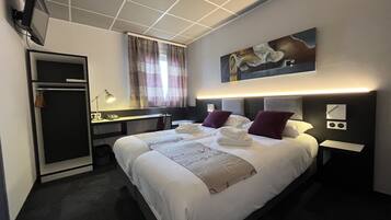 Een hotelkamer met een bed, een bureau, een stoel, een kledingkast en een televisie.