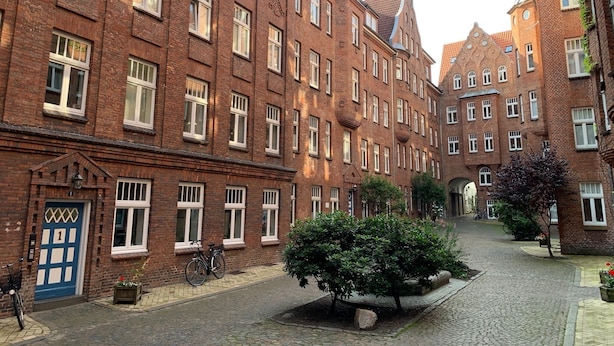 Een straat met kinderaarsbekleding bezaaid met kinderaarsbekleding, met een centrale tuin, een struik en een fiets bij de ingang.