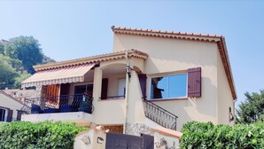 A two-story house with a balcony, a tiled roof, and a stone facade.
