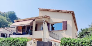 Ein zweistöckiges Haus mit Balkon, Ziegeldach und Natursteinfassade.