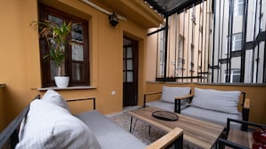 Un espace extérieur accueillant, aménagé avec un canapé, une table en bois et une plante en pot.