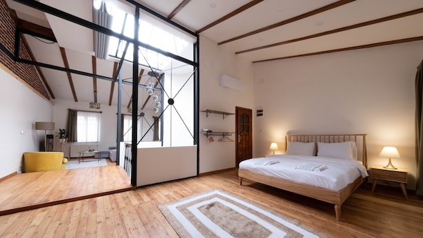 Une chambre spacieuse avec un grand lit, un plancher en bois et un puits de lumière.