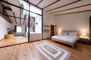 A spacious bedroom with a large bed, wooden flooring, and a skylight. - Penthouse in the Heart of Pera (Istanbul)