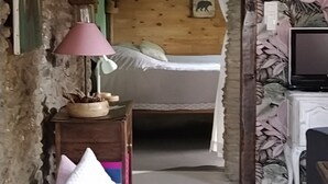 Une pièce confortable avec un lit, une lampe, une petite table et un téléviseur.