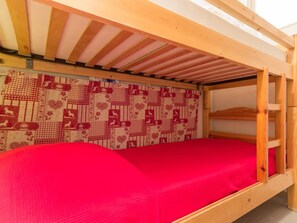 Ein Stockbett mit einer roten Matratze und einer Wand mit Muster.