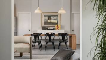 Un comedor moderno con una mesa de madera, sillas negras e iluminación colgante.