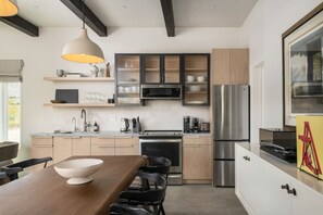 A modern kitchen with a central island, stainless steel appliances, and a large window.