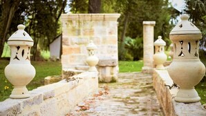 A stone pathway with lanterns and a stone wall in a garden setting.
