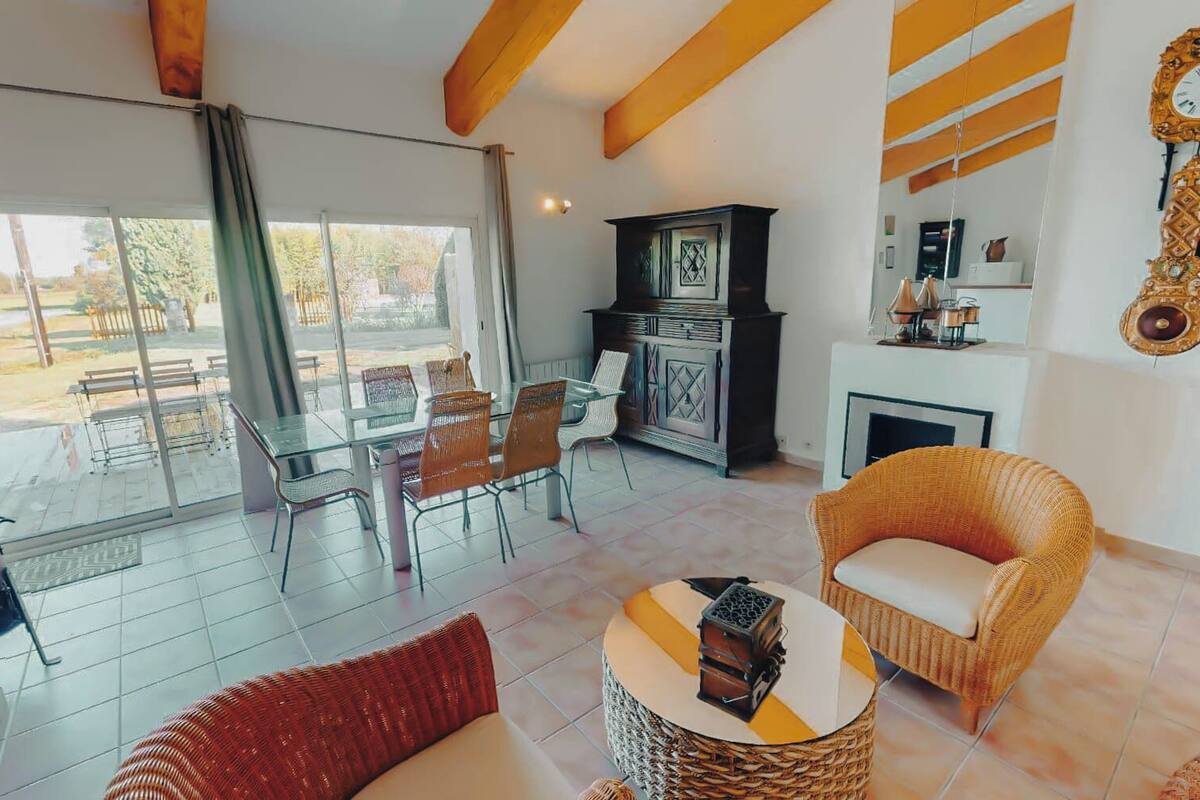 A spacious living area with a glass door leading to an outdoor patio, wicker furniture, a fireplace, and a decorative wall clock.