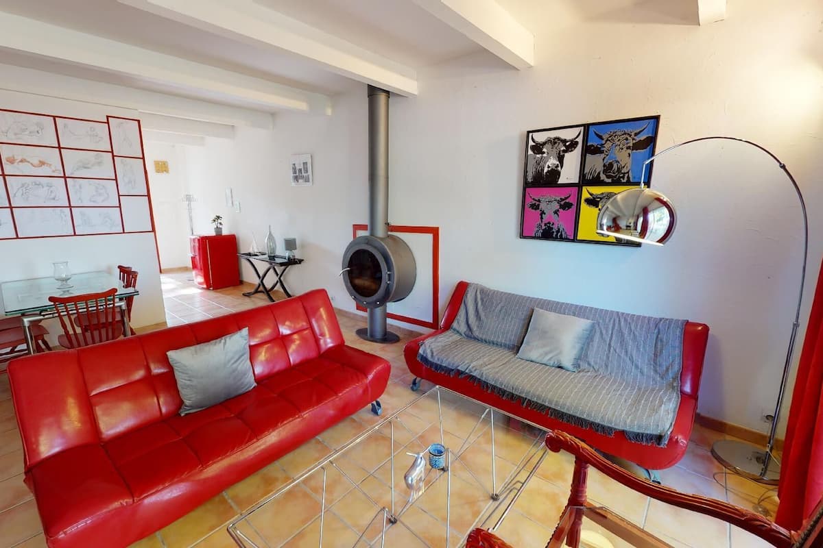 A living room with a red sofa, a grey sofa, a dining area with a glass table, and a modern fireplace.