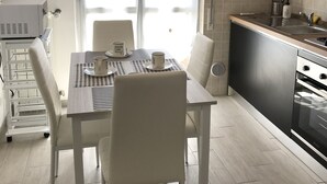 Ett modernt kök med matplats, utrustat med en köksö, en inbyggd ugn och ett fönster med hjärtformade utskärningar.