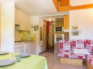 A compact kitchen with a microwave, oven, and a dining area with a table set for two.