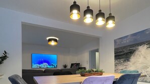 A modern dining area with a wooden table, four chairs, and a flat-screen TV.