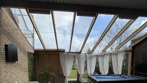 An indoor patio with a pool table, seating area, and a view through a skylight.
