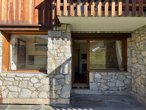 A stone facade with a wooden balcony and large windows. - 5 person apartment at the foot of the slopes with terrace, pets allowed (Belle Plagne)