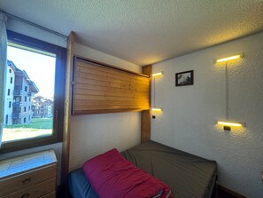 A room with a bed, a window, a wooden headboard, a wall-mounted light, and a small picture. - 5 person apartment at the foot of the slopes with terrace, pets allowed (Belle Plagne)