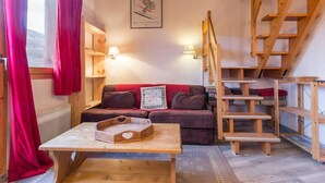A cozy room with a wooden staircase, a sofa, a table with a tray, and a poster on the wall.