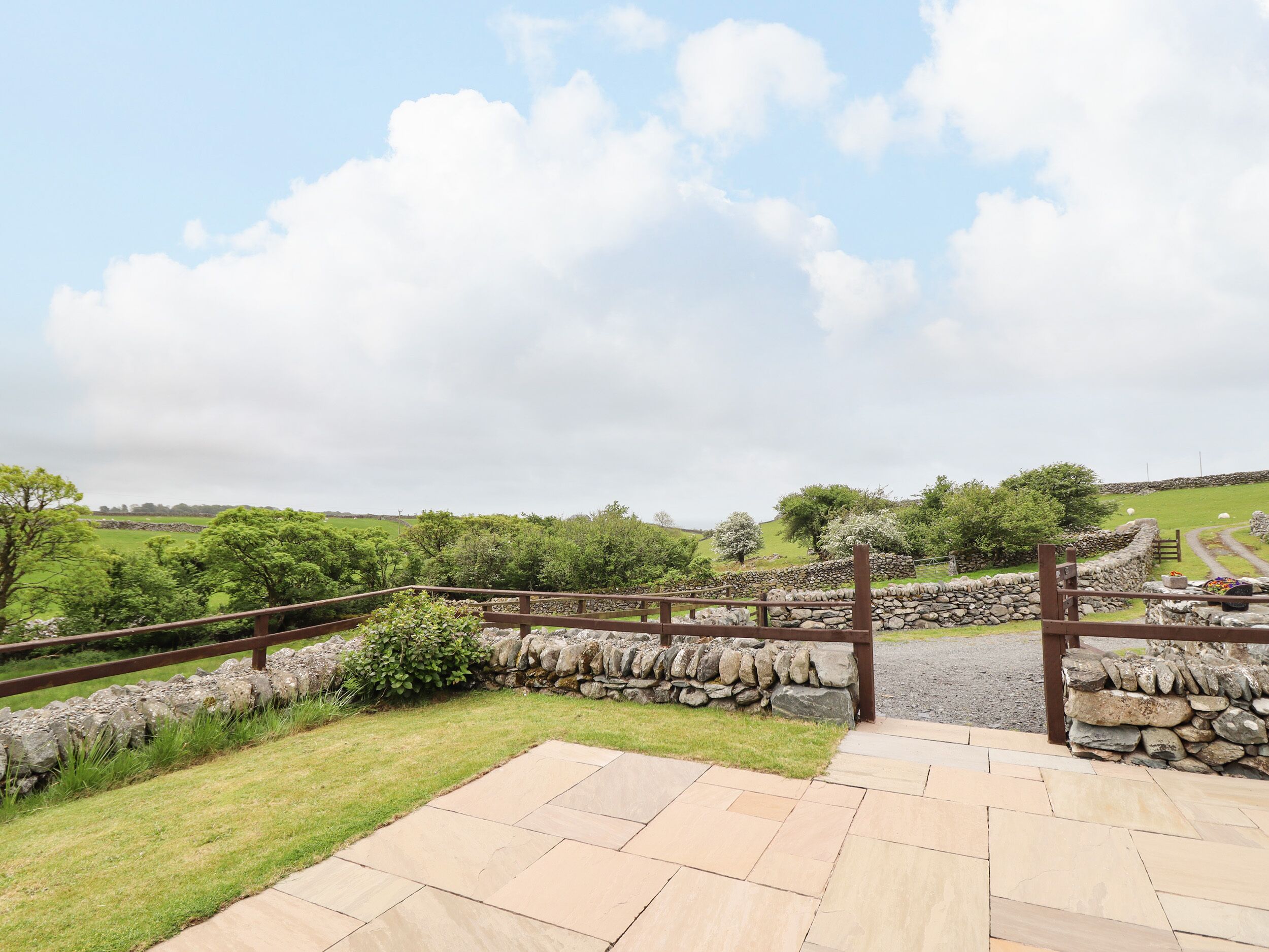 A stone pathway leading to a stone wall with a wooden fence.