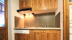 Cucina con mobili in legno, forno integrato e lavello in acciaio inossidabile.