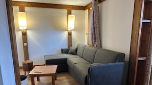 Un accogliente soggiorno con un divano componibile, un tavolino in legno e due lampade a parete.