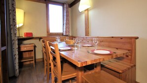 Un tavolo da pranzo in legno con quattro sedie, una panca e una finestra con tende.