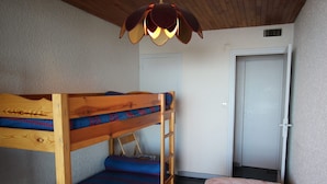 Habitación con literas de madera, una cama individual, un tapete estampado y una lámpara en el techo.
