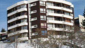 Un edificio residencial de varios pisos con balcones, techo plano y cielo despejado.