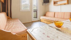 Ein gemütliches Zimmer mit einer Couch, einem Tisch mit einer Schüssel und einem an der Wand befestigten Fernseher.