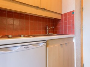 Et køkken med en Whirlpool opvaskemaskine, en vask og en backsplash med røde fliser.