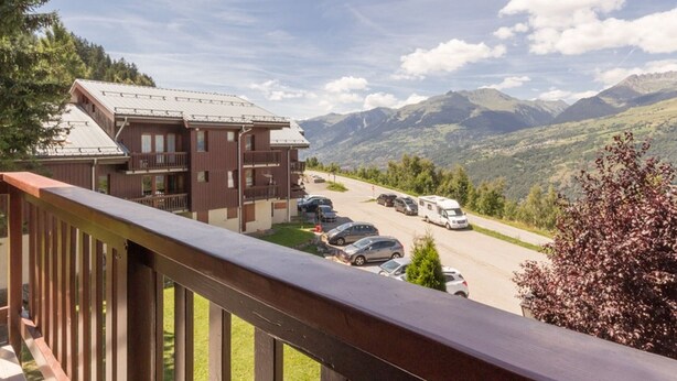 Eine Berghütte mit Parkplatz und Blick auf die umliegenden Berge.