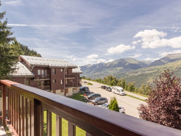 A mountain lodge with a parking area and a view of the surrounding mountains.