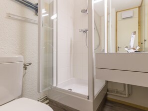 A bathroom with a glass-enclosed shower, a toilet, and a sink with a mirror.