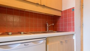 Eine Küche mit einem Geschirrspüler von Whirlpool, einem Spülbecken und roten Fliesen.