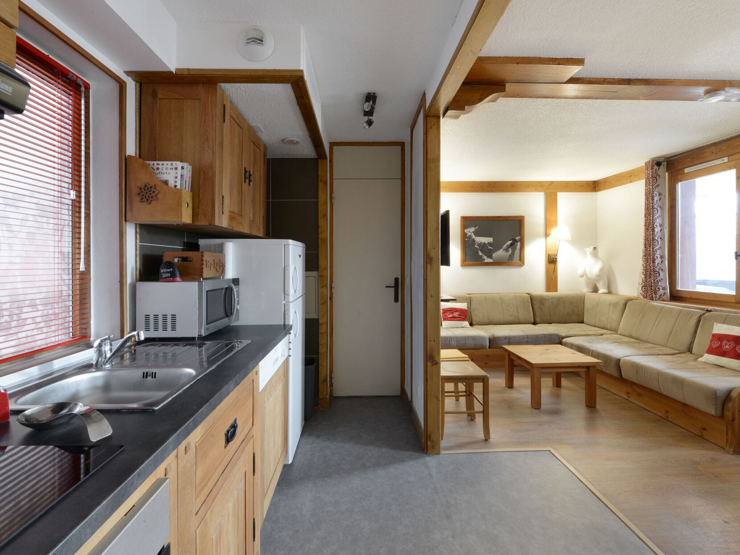 A compact kitchen with modern appliances, a dining area with a sofa and table, and a view of the outdoors through a window.