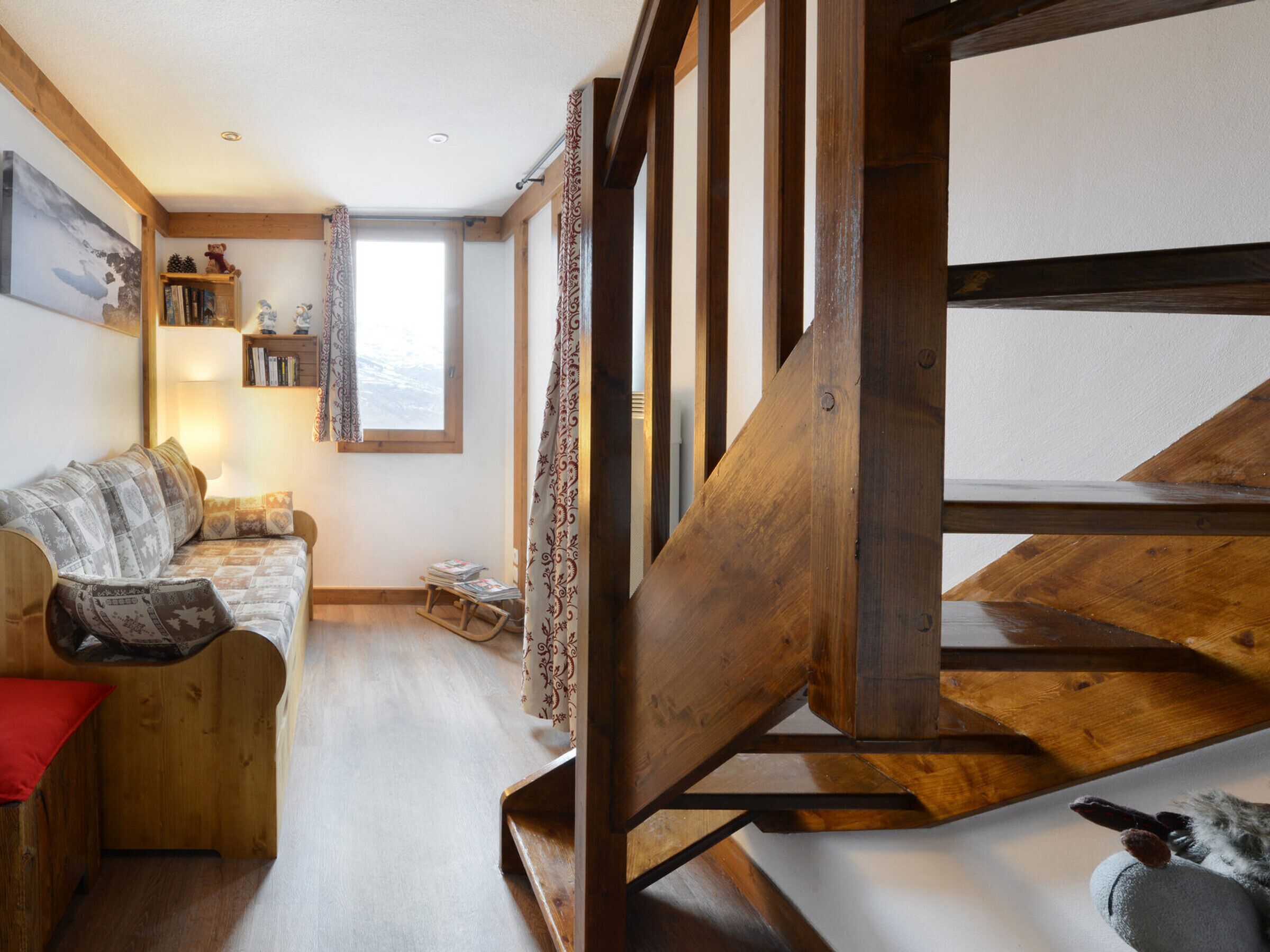 Een gezellige kamer met een houten trap, een bank en een boekenkast.
