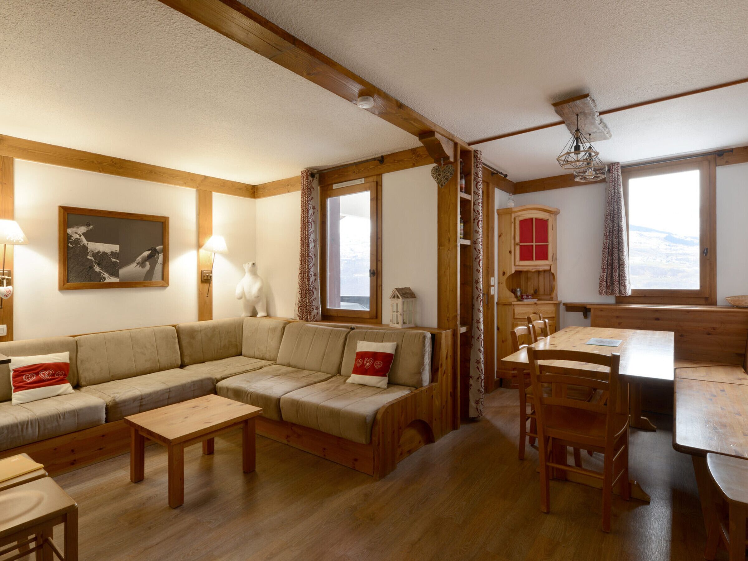 Ein gemütliches Wohnzimmer mit Sofa, Couchtisch und Esstisch. Ein Fenster mit Blick, eine Lampe und ein Bild an der Wand sind ebenfalls zu sehen.