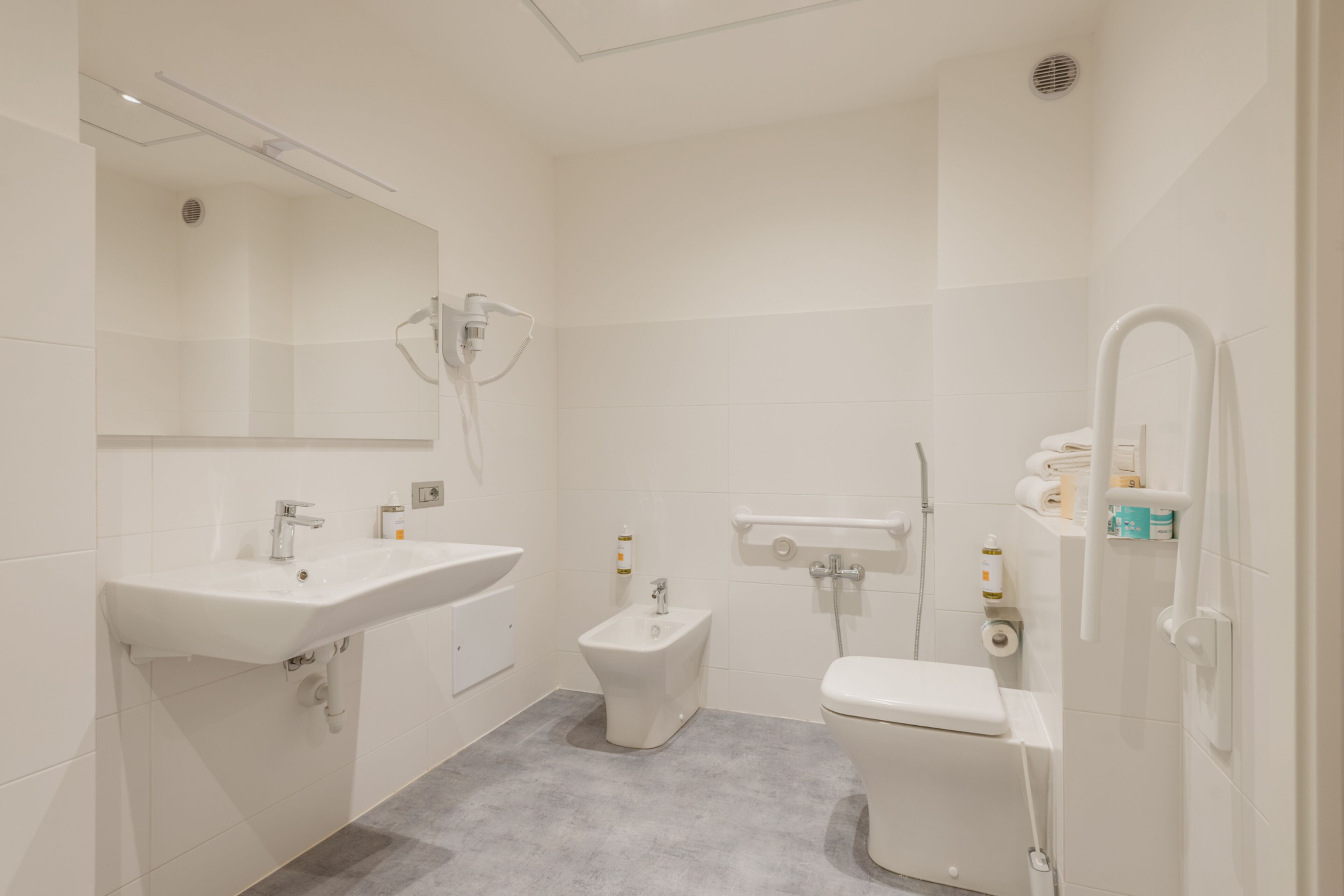 Un baño moderno con lavamanos, bidé, inodoro y ducha.