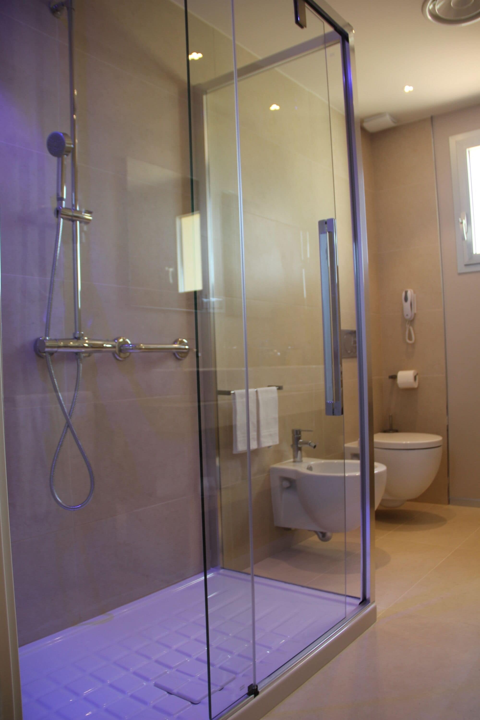 Een moderne badkamer met een douchecabine van glas, een wastafel en een toilet.