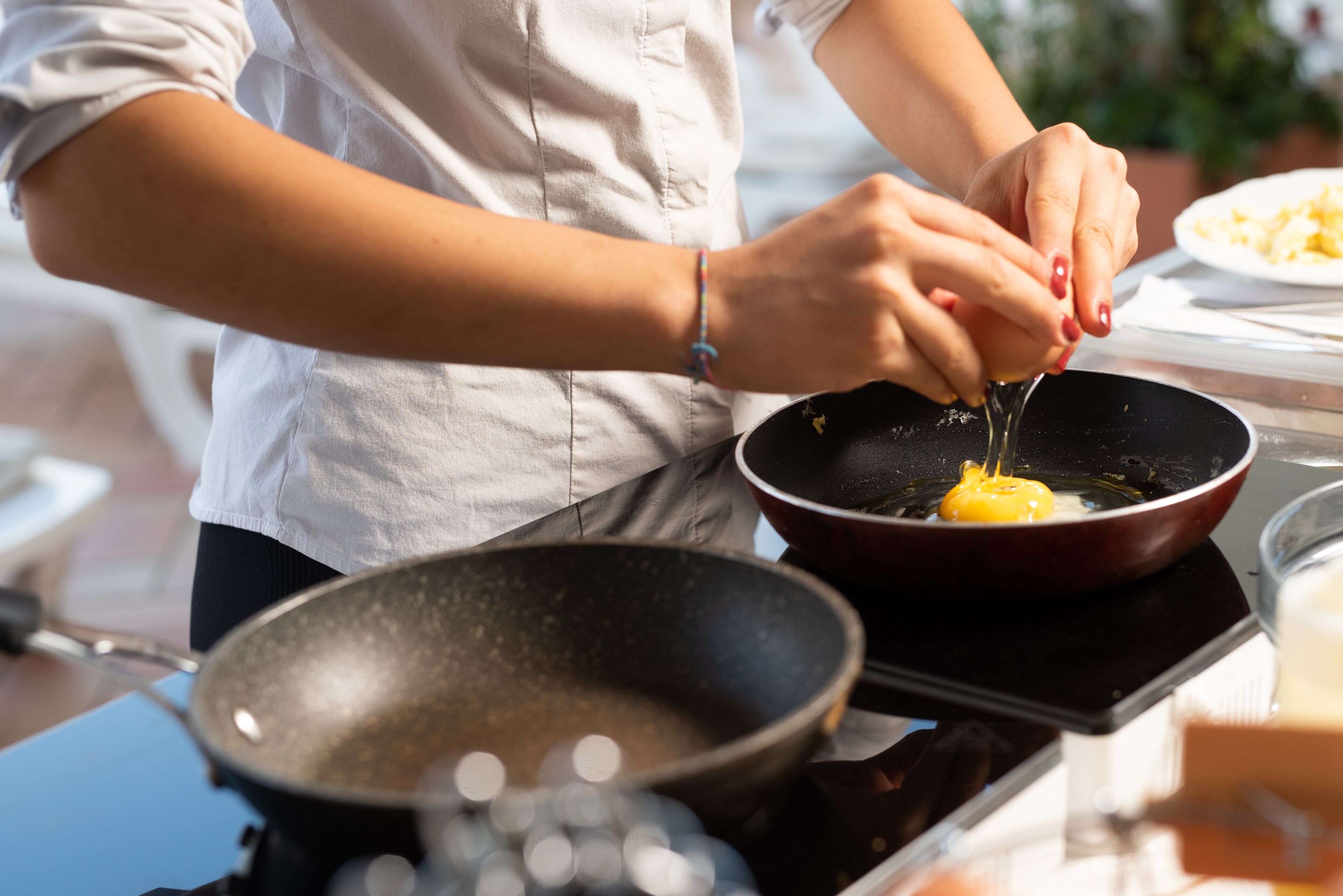 A person cooking an egg in a pan on a stove.