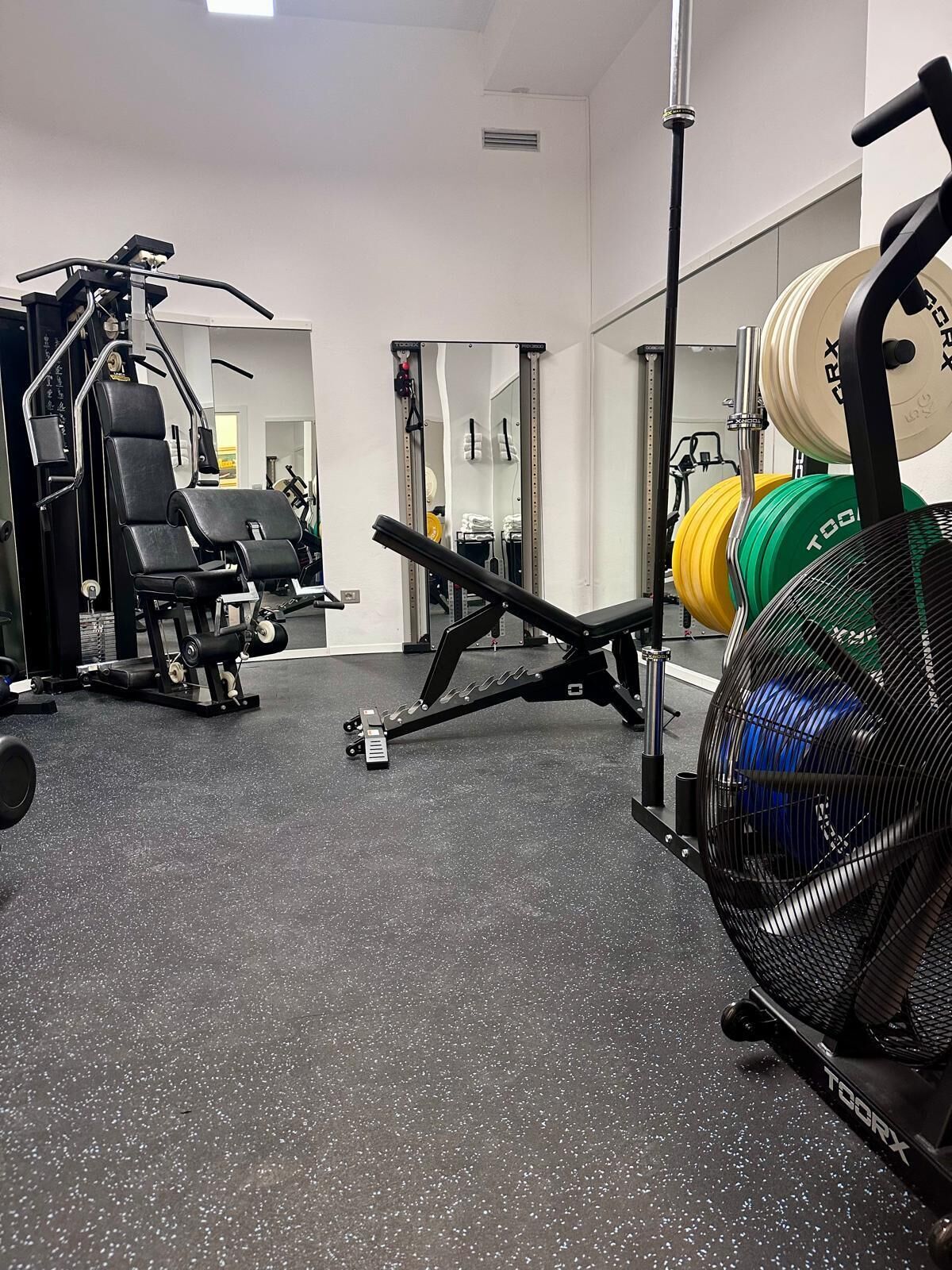 A gym with weightlifting equipment, a mirror, and a weight rack.