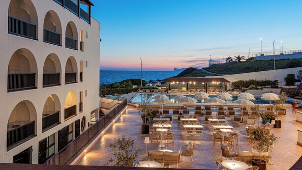 Um bar no terraço com mesas ao ar livre e vista para o mar.