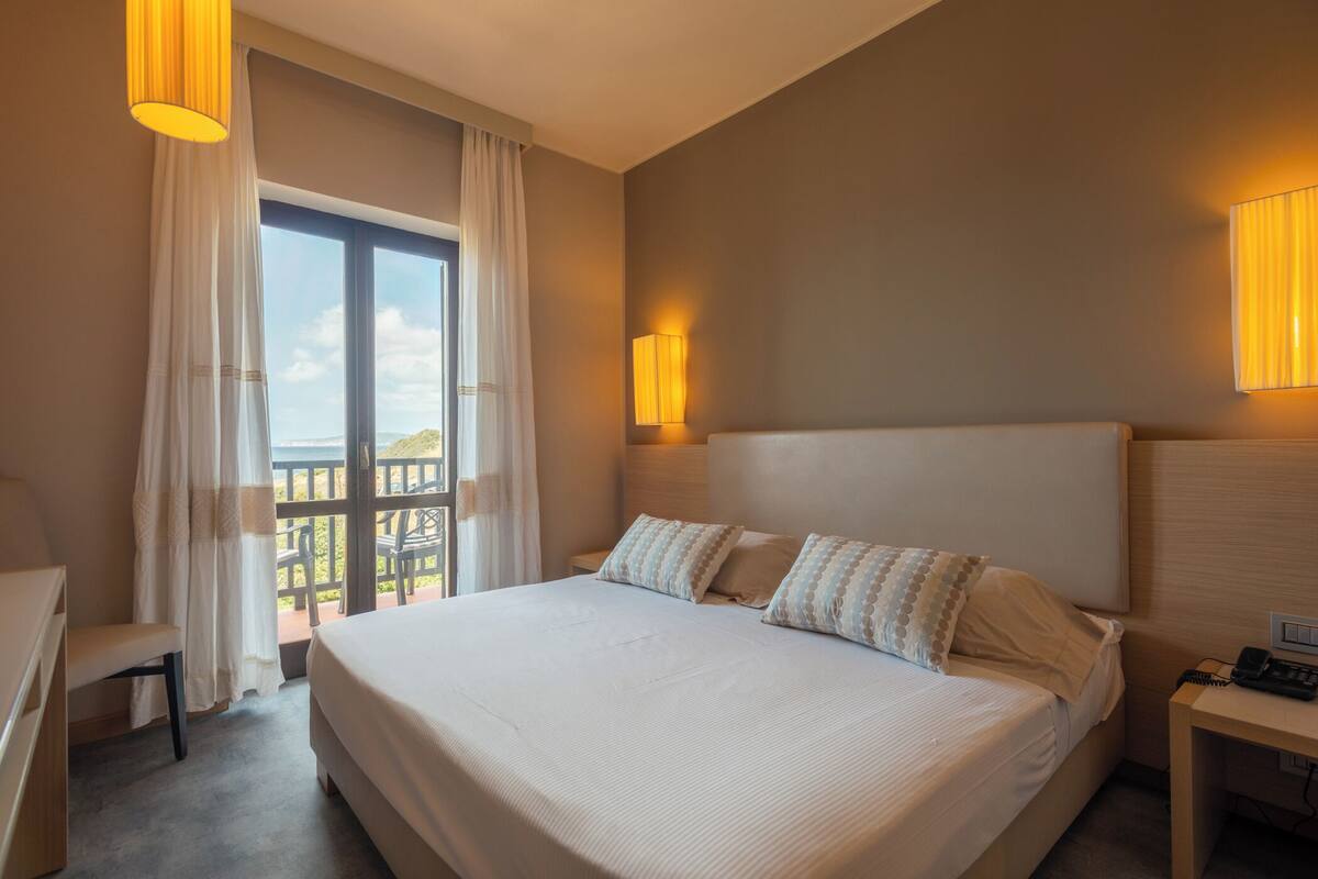 Une chambre d’hôtel avec un grand lit, un bureau, une chaise et un balcon avec vue.