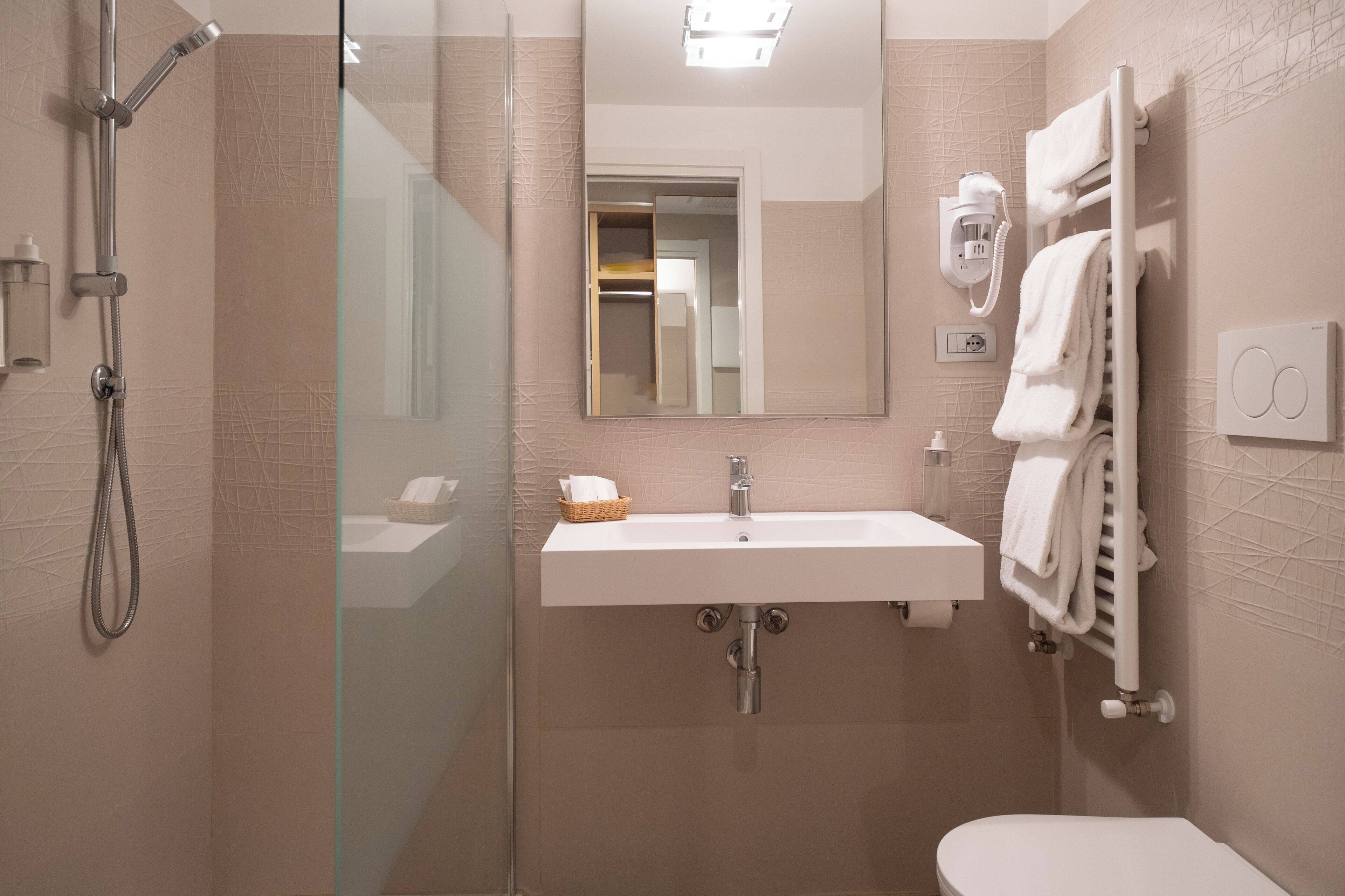 A modern bathroom with a glass-enclosed shower, a white sink, and a towel rack.