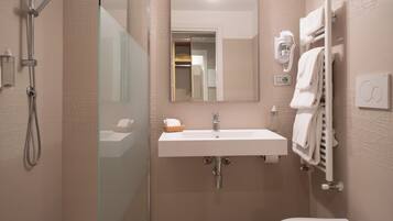 Un baño moderno con ducha envuelta en vidrio, un lavabo blanco y un perchero para toallas.
