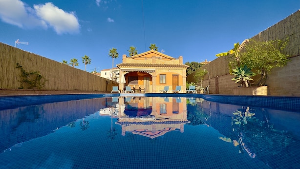 Una piscina con vista chiara su un edificio con tetto in tegole e un balcone.