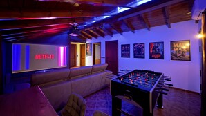 Una stanza accogliente con un tavolo da calcio, un divano e un grande schermo che mostra il logo di Netflix.