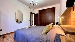 Una camera da letto con un letto, un armadio in legno, uno specchio e un lampadario.