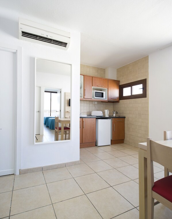 A compact kitchen with a microwave, refrigerator, and wooden cabinets.