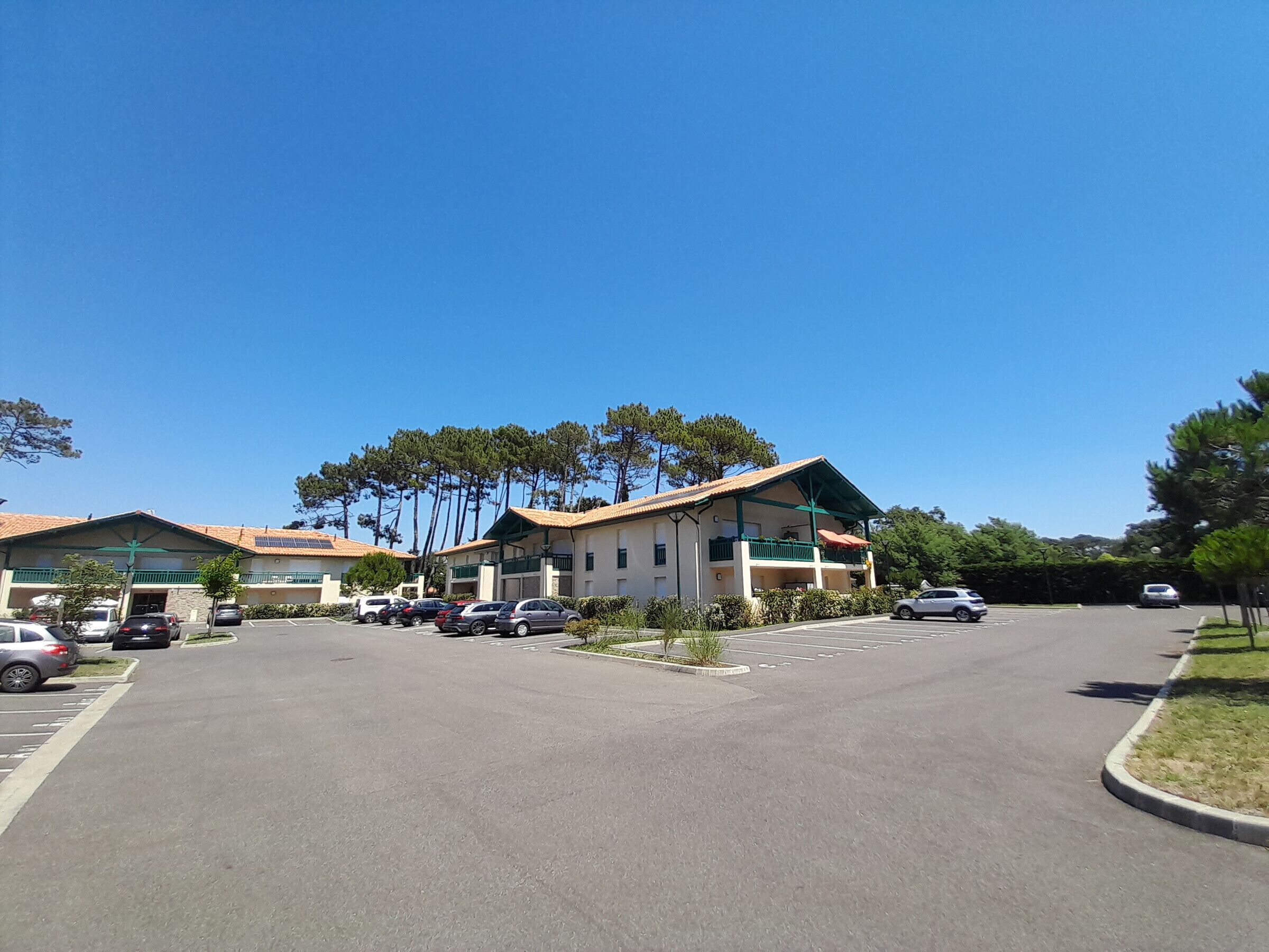 Ein Hotel mit mehreren Gebäuden, einem Parkplatz und Bäumen.