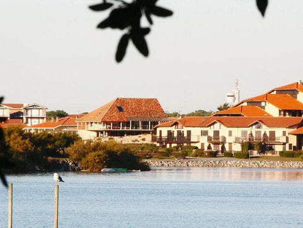 A coastal building complex with multiple structures, a clear view of the water, and a bird perched on a post.